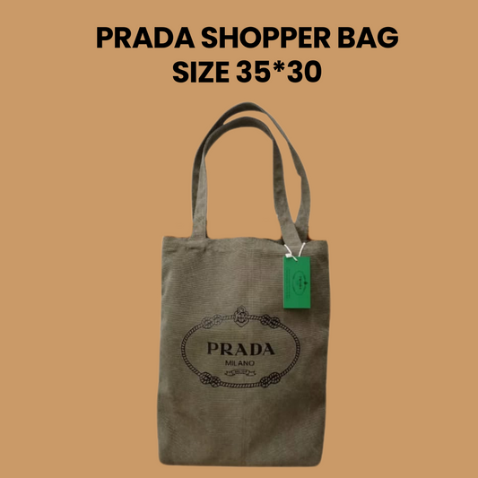 Prada shopper bag with black logo and green tag, size 35x30 cm, displayed on beige background.
#PradaShopperBag #DesignerTote #LuxuryAccessories #PradaMilano #EcoFriendlyFashion #MinimalistStyle #FashionEssentials #EverydayTote #35x30Bag #PradaStyle