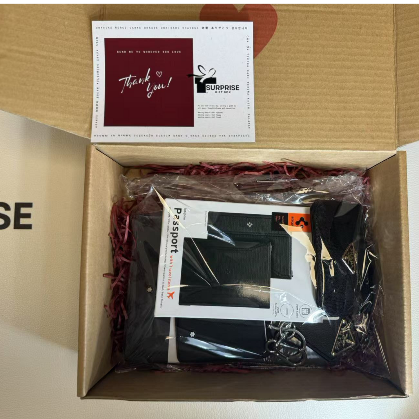 Unopened box with 'Surprise Box' branding and items inside, surpriseboxgift.com with thank you card, spigen passport cover 