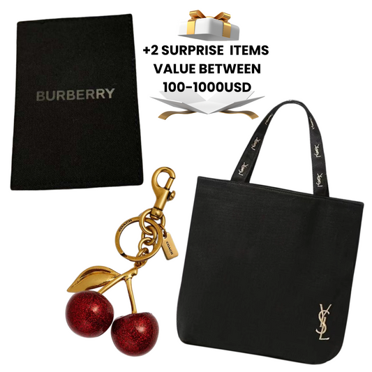 Black Burberry bag, gold cherry keychain, and black tote bag with YSL logo on a white background.